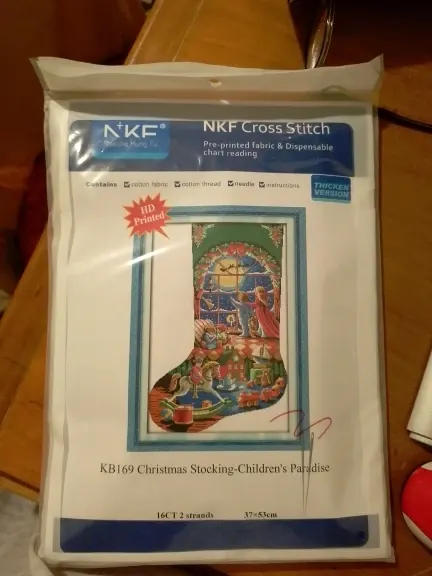 An opened Christmas stocking cross stitch kit pouch showing the printed Aida fabric, sorted threads and instruction sheet