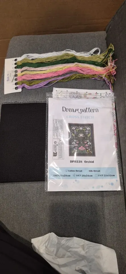 Buyer photo of the Orchid kit contents: black Aida fabric, the DPH338 chart pouch and rows of green, pink and lilac threads